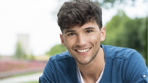 Young man in blue shirt smiling outdoors