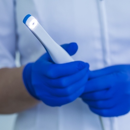 Dental professional holding a thin white intraoral camera