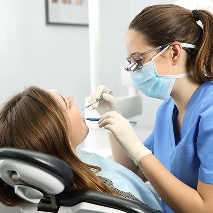 Hygienist examining woman’s teeth and gums