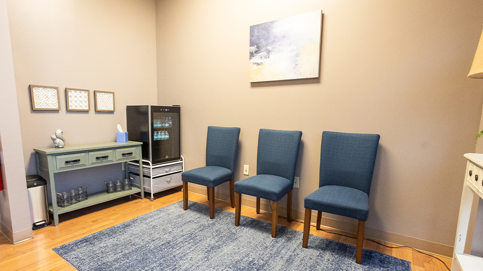 Blue chairs next to mini fridge with waterbottles