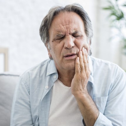 Older man holding the side of his jaw in pain