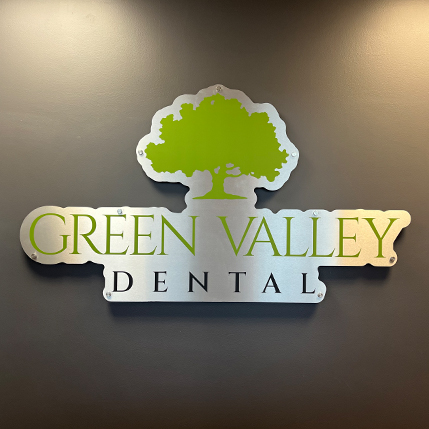 Green Valley Dental sign on wall with green tree logo