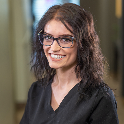 Smiling dental team member with glasses and brown hair